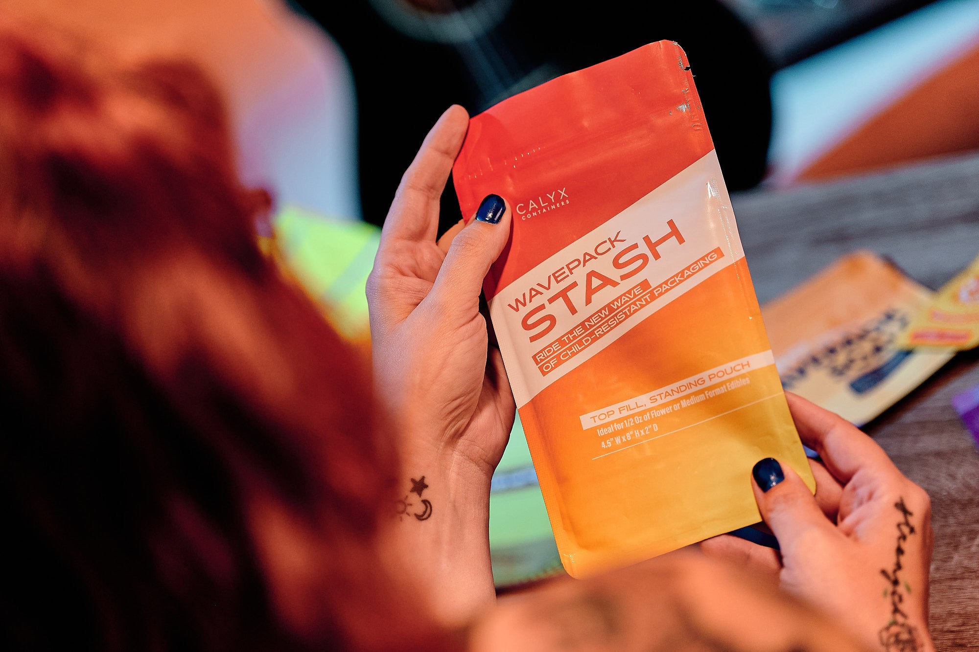Person holding a flexible cannabis package 'Wavepack Stash' product packaging with a blurred background