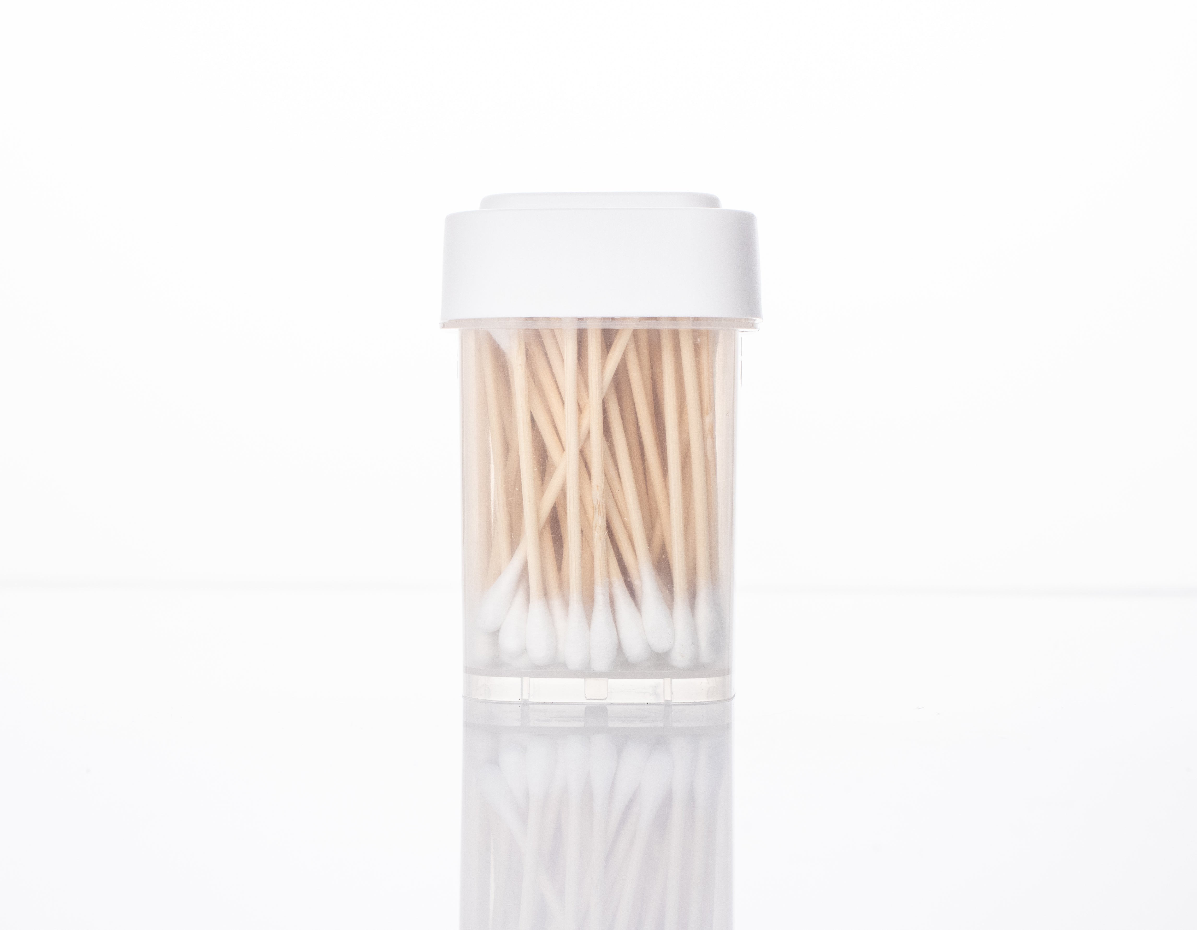 Clear plastic packaging with a white lid and cotton swabs inside.