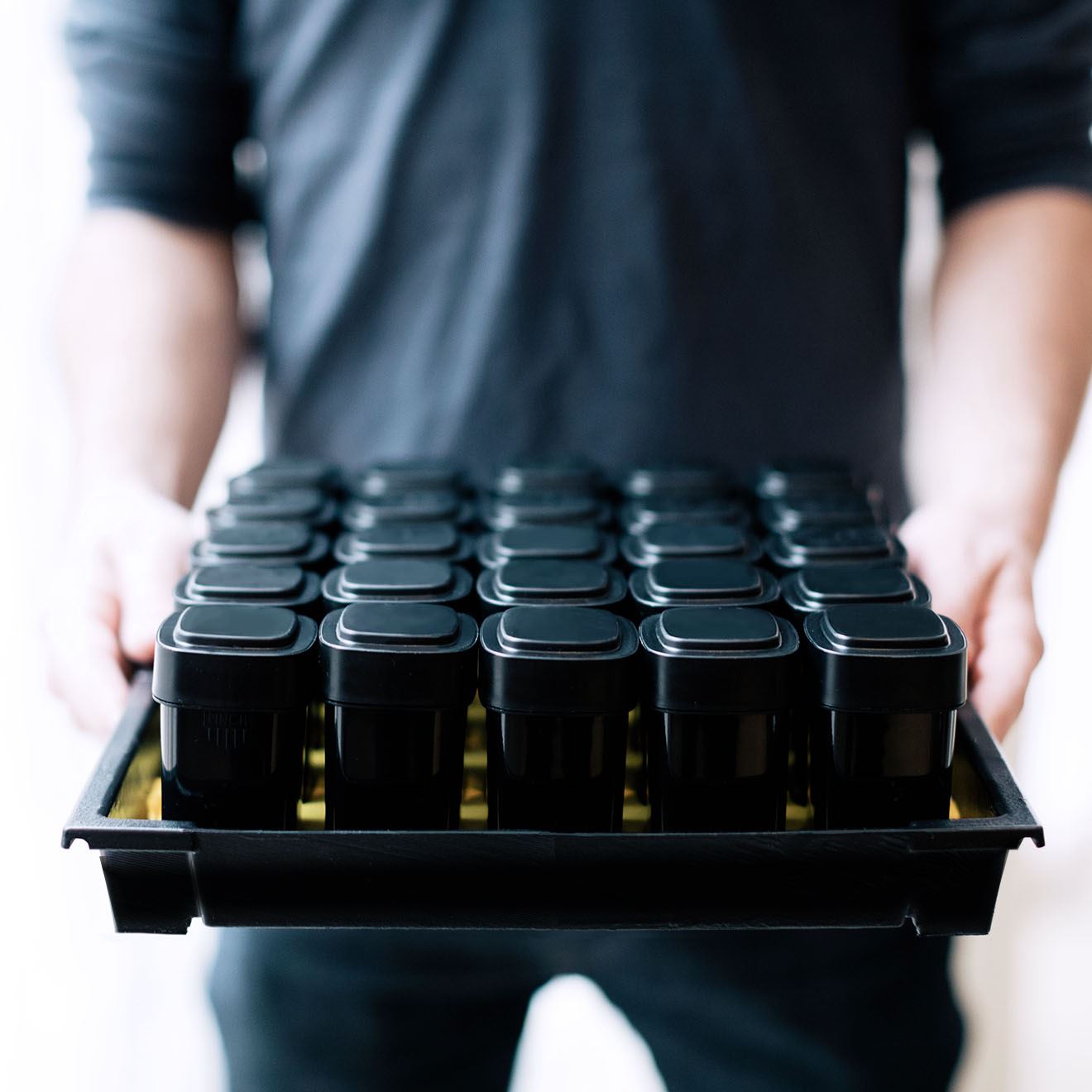 Man holding an insert filled with opaque, black Calyx dram containers