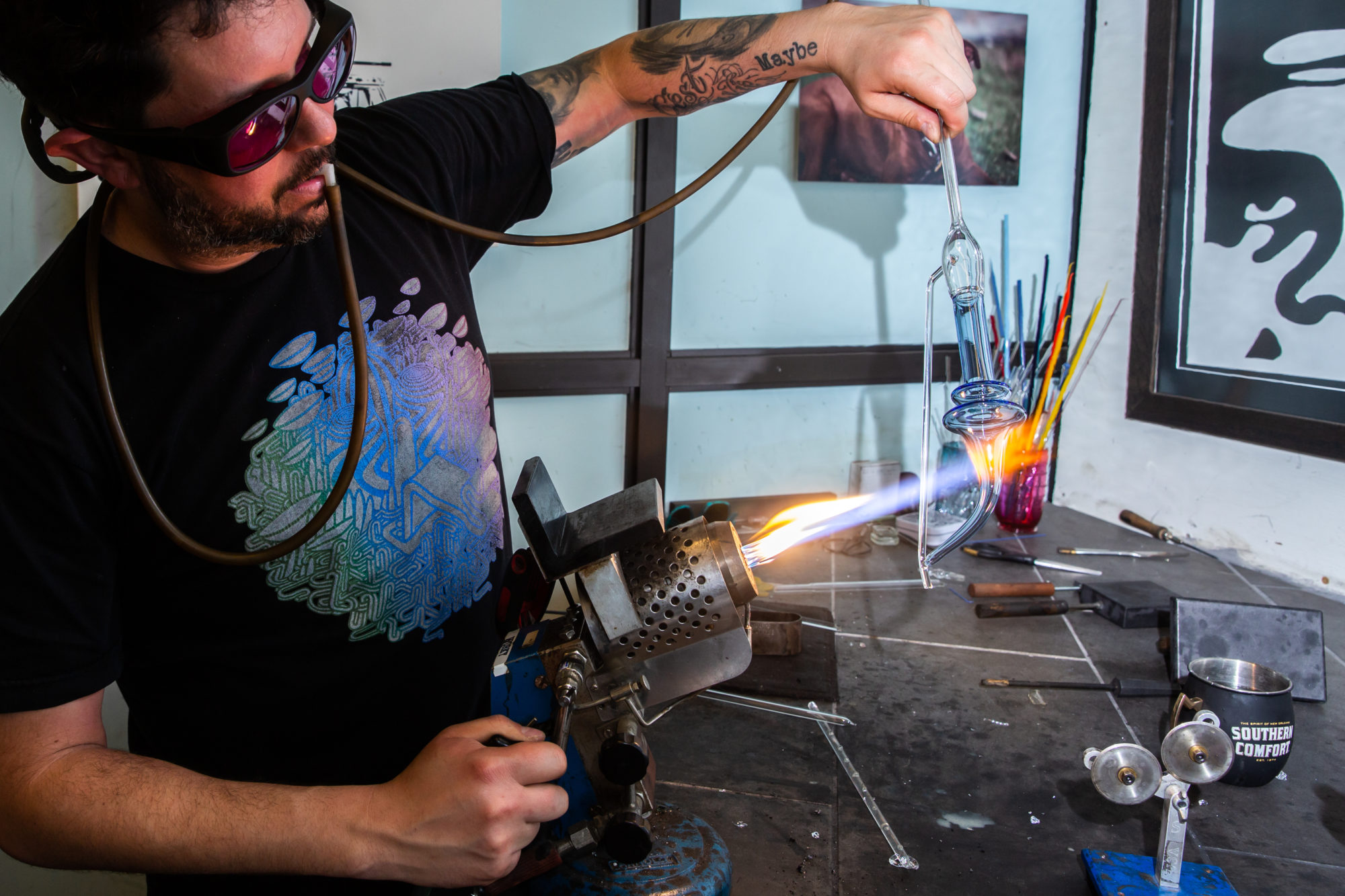 Vela G blowing a custom light blue glass tube over an open flame